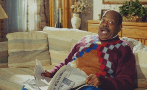 a man sitting on a couch reading a newspaper that says chronicle