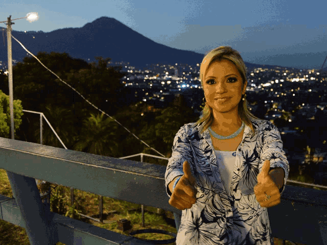 a woman is giving a thumbs up in front of a mountain