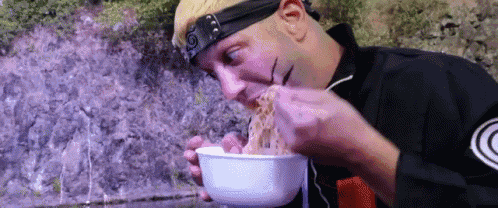 a man in a costume is eating noodles from a bowl with a fork .