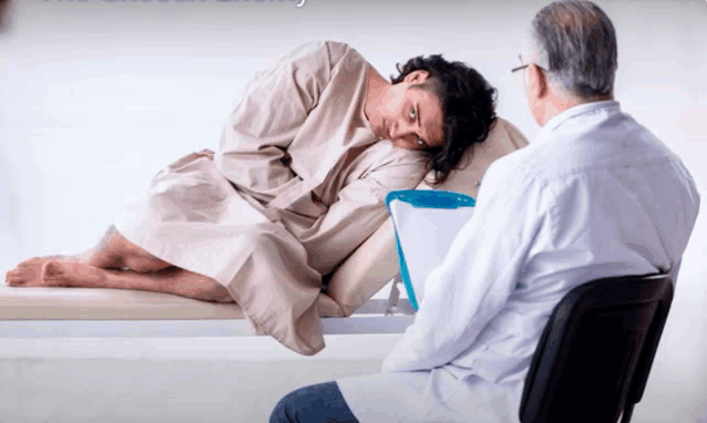 a man in a hospital gown sits on a bed with a doctor
