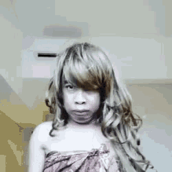 a woman with long hair is wearing a wig and a towel around her neck .