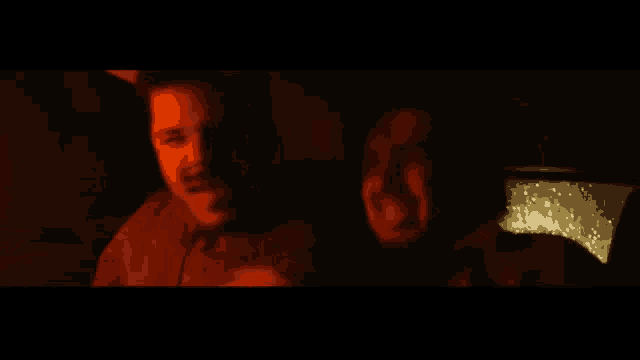 two men are sitting in the back seat of a car with a red light behind them