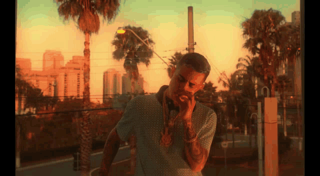 a man smoking a cigarette in front of palm trees and buildings