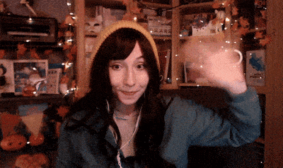 a girl wearing a yellow beanie and a blue jacket waves her hand
