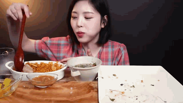 a woman is sitting at a table eating food with a spoon .