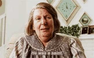 an elderly woman sitting in a chair with the words he was a saint on her shirt
