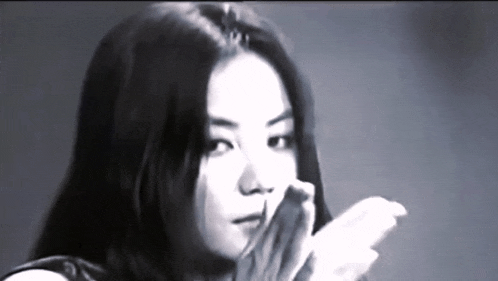a woman with long hair is covering her mouth with her hands