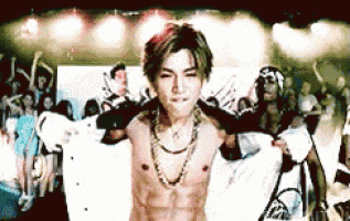 a shirtless man is dancing on a stage with a crowd behind him .