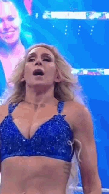 a woman in a blue bra is standing in a ring on a stage .