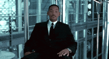 a man in a suit and tie sits on a chair