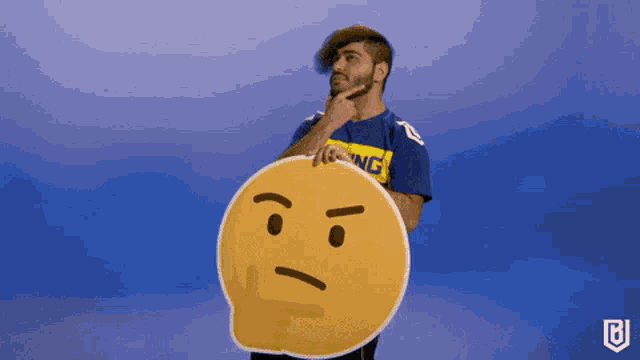 a man in a blue shirt with the word king on it is holding a smiley face