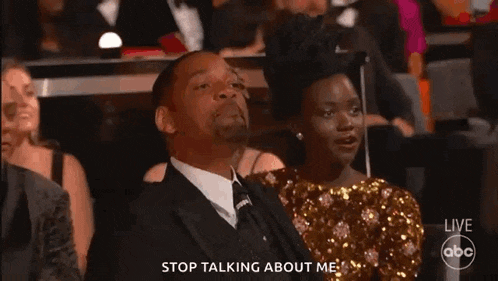 a man in a suit and tie is laughing while sitting in a theatre .