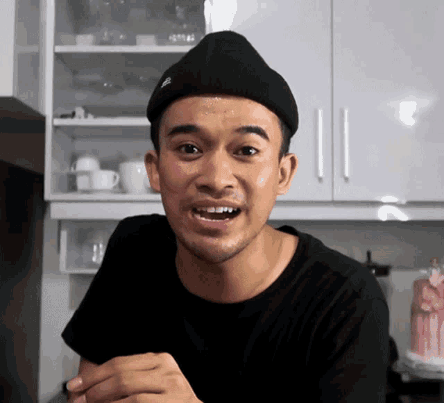 a man wearing a black hat and a black shirt is making a face