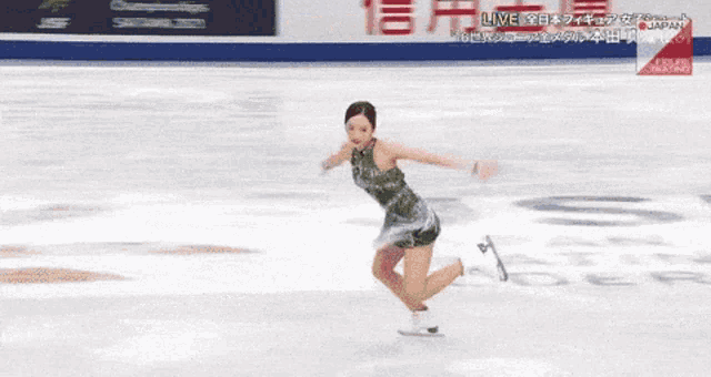 a woman in a green dress is ice skating in front of a sign that says live japan