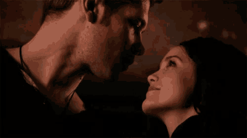 a man and a woman are looking at each other in the dark