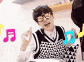 a person wearing glasses and a vest is sitting on the floor with a music note in the background .