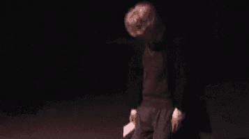 a woman is laying on the floor in a dark room with her head on the floor .