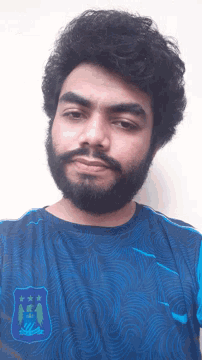 a man with a beard wears a blue shirt that says city