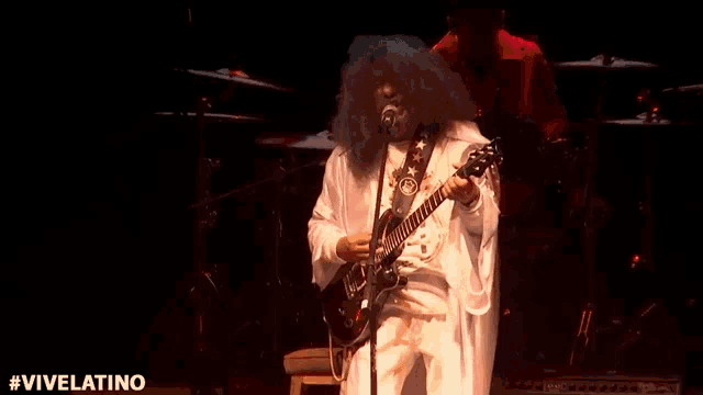 a man with a beard is playing a guitar and singing into a microphone on stage