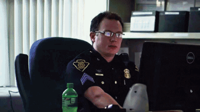 a police officer is sitting at a desk with a dell computer
