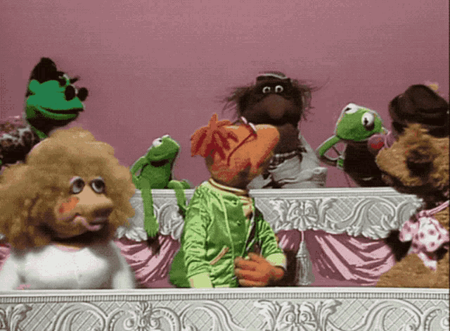 a group of stuffed animals including kermit the frog are standing on a stage
