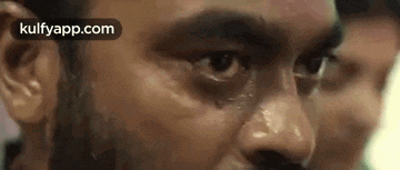 a close up of a man 's face with a tear coming out of his eyes .