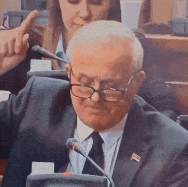 a man in a suit and tie with a flag on his collar is giving a thumbs up