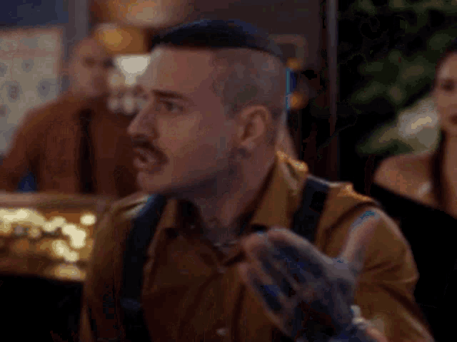 a man with a mohawk and suspenders is talking to a woman in a bar .