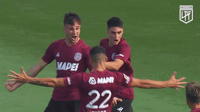 a soccer player with the number 22 on his back is hugged by other players