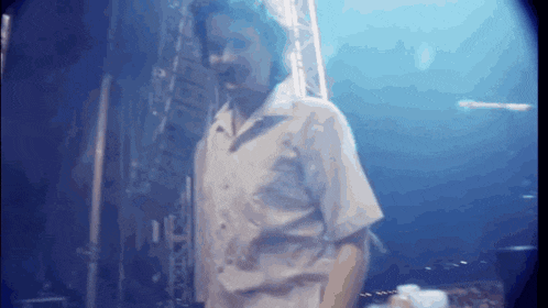 a man in a white shirt is standing in front of a blue wall .