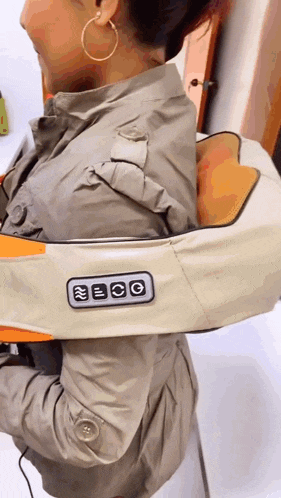 a woman wearing a tan jacket has a device on her shoulder that says eco