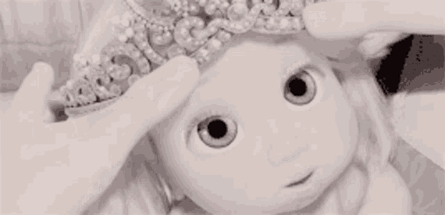 a person is putting a crown on a baby doll .