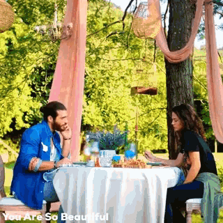 a man and a woman are sitting at a table with the words " you are so beautiful " on the bottom