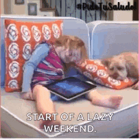 a little girl is sitting on a couch using a tablet .