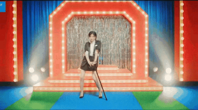 a woman is standing on a stage with a cane in her hand