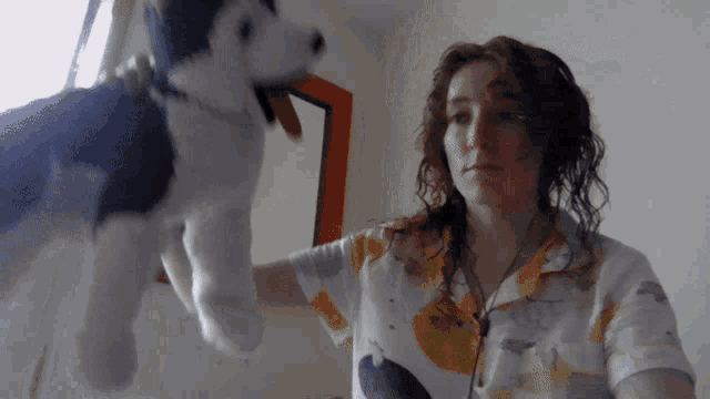 a woman is holding a stuffed husky dog in front of a mirror