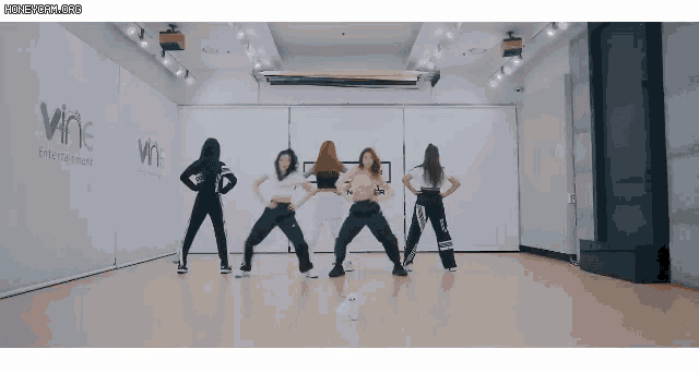 a group of girls are dancing in a dance studio with the words wne entertainment on the wall
