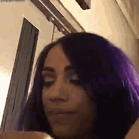 a close up of a woman with purple hair making a face .