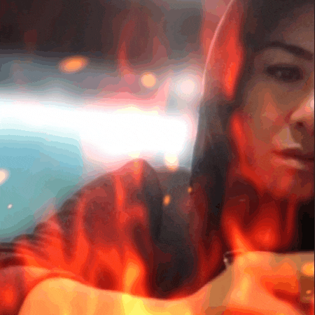 a close up of a person 's face with fire behind them