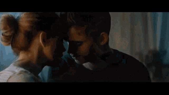 a man and a woman are kissing in a room in a movie .