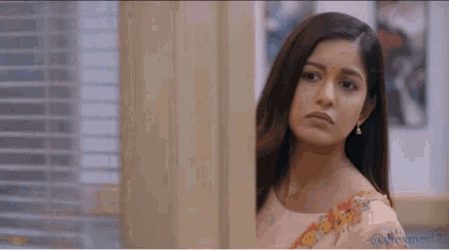 a woman with long hair is standing in front of a door looking at the camera .