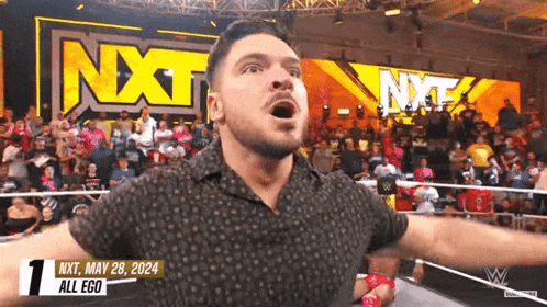 a man in a wrestling ring with the nxt logo behind him