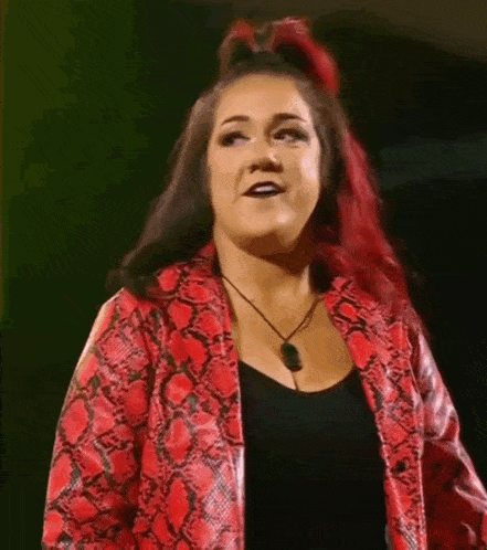 a woman with red hair is wearing a red snakeskin jacket and black top .