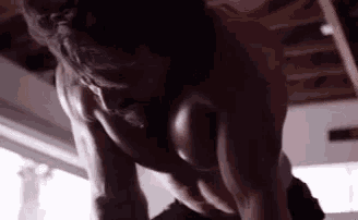 a man without a shirt is doing push ups on a bar in a gym .