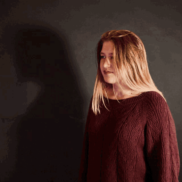 a woman wearing a maroon sweater is looking down