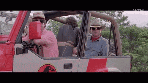 a man in a pink shirt is driving a red and white jeep .
