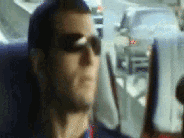 a man wearing sunglasses is sitting in a car looking out the window