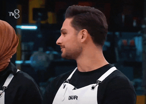 a man wearing an apron that says onur looks to the side