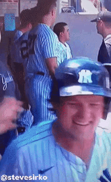 a man wearing a new york yankees baseball helmet smiles