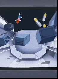 a computer screen shows a room with boxes and capsules flying around